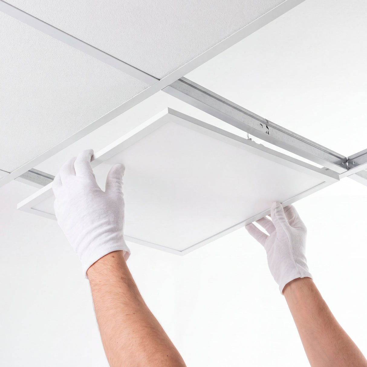 Técnico calificado insertando un panel difusor en la cuadrícula de un cielo raso suspendido modular.