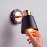 Proceso de colocación de bombilla E27 en luminaria orientable de pared con pantalla negra.