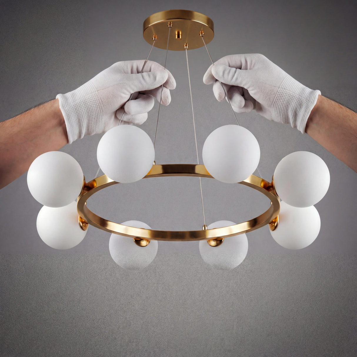 Manos profesionales instalando la lampara Collier Gold asegurando el soporte del dosel dorado al techo.