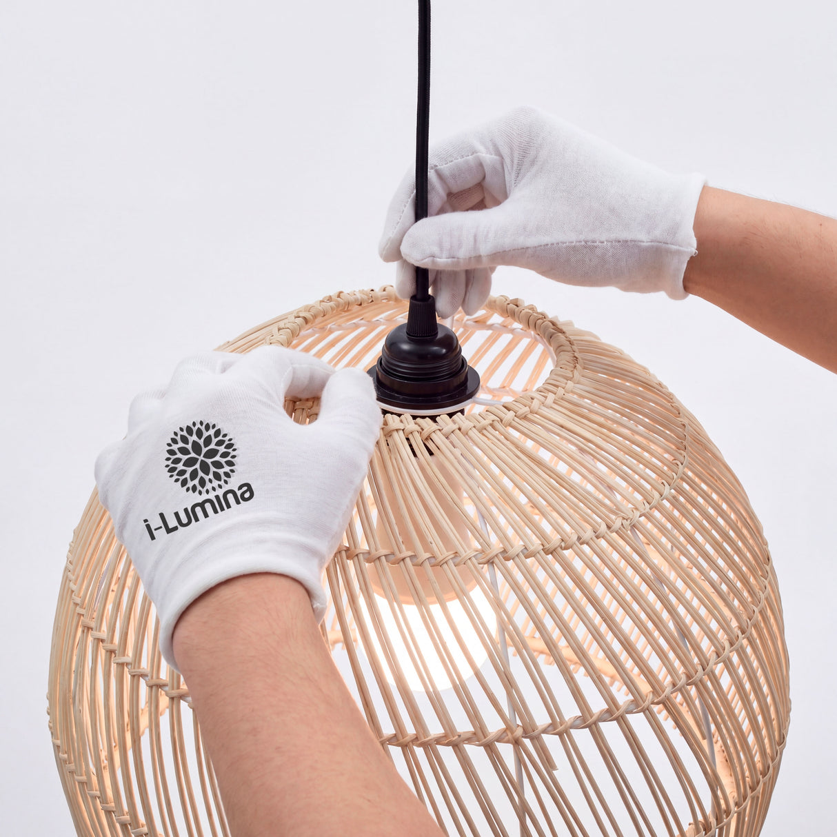 Ajuste manual de porta-lámparas en campana de rattan con guantes de protección blanca.