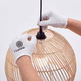 Ajuste manual de porta-lámparas en campana de rattan con guantes de protección blanca.