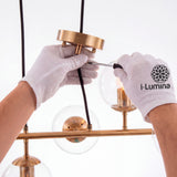 Especialista ajustando el sistema de doble cable de la lámpara utilizando guantes blancos.