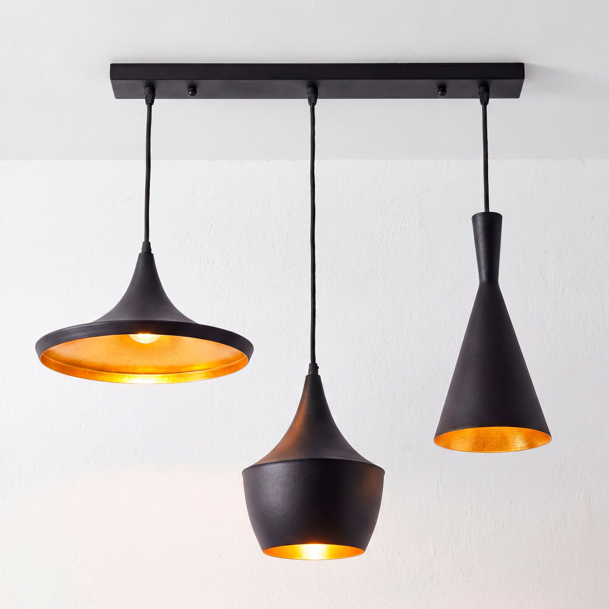 Canopla rectangular negra instalada con tres lámparas de estilo industrial negro y oro.