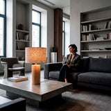 Lámpara de madera clara en salón de estilo industrial con mobiliario de hormigón.