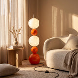 Rincón de salón minimalista decorado con una luminaria vertical de esferas y un sillón curvo.