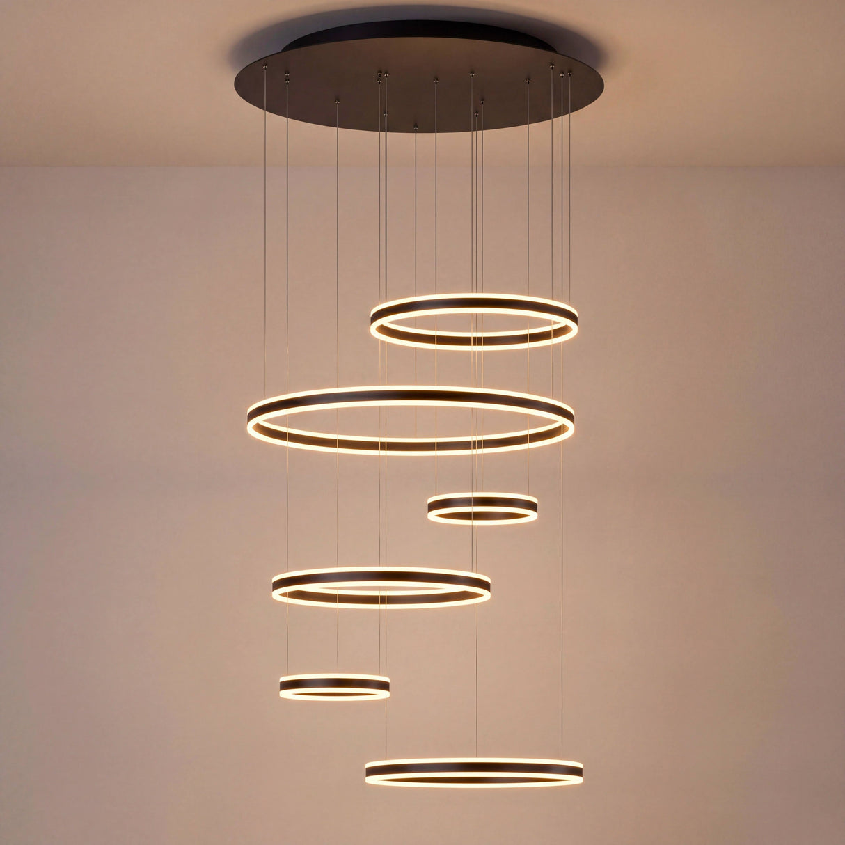 Aros de luz LED suspendidos en cascada geométrica, ideal para proyectos arquitectónicos de diseño interior moderno.