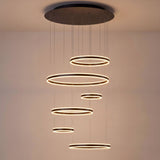 Aros de luz LED suspendidos en cascada geométrica, ideal para proyectos arquitectónicos de diseño interior moderno.