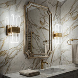 Lampara de pared Flow Gold instalada sobre pared de marmol en un baño elegante.