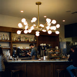 Aplicacion de la lampara Sputnik Nativa Gold sobre la barra de un bar moderno.