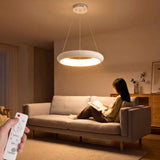Luminaria LED circular blanca sobre sofá gris en salón de diseño nórdico con luz cálida.