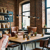 Lampara colgante de estilo industrial negro mate instalada en mesa de cafeteria.