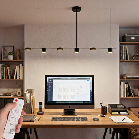 Lampara colgante lineal led negra sobre escritorio de oficina moderna con luz calida.