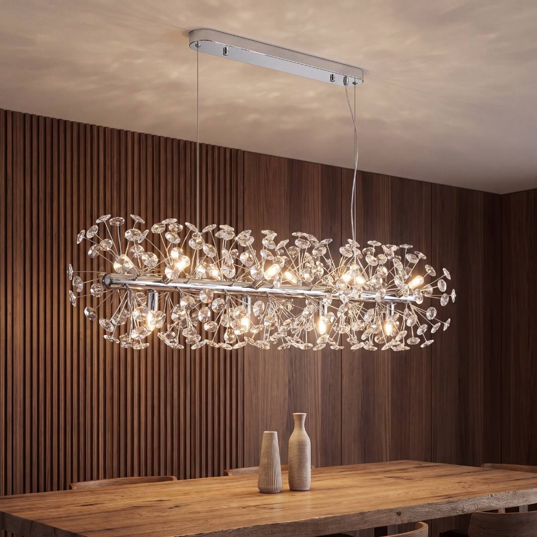 Lámpara colgante MESSIE de cristal K9 cromada encendida sobre una mesa de comedor de madera