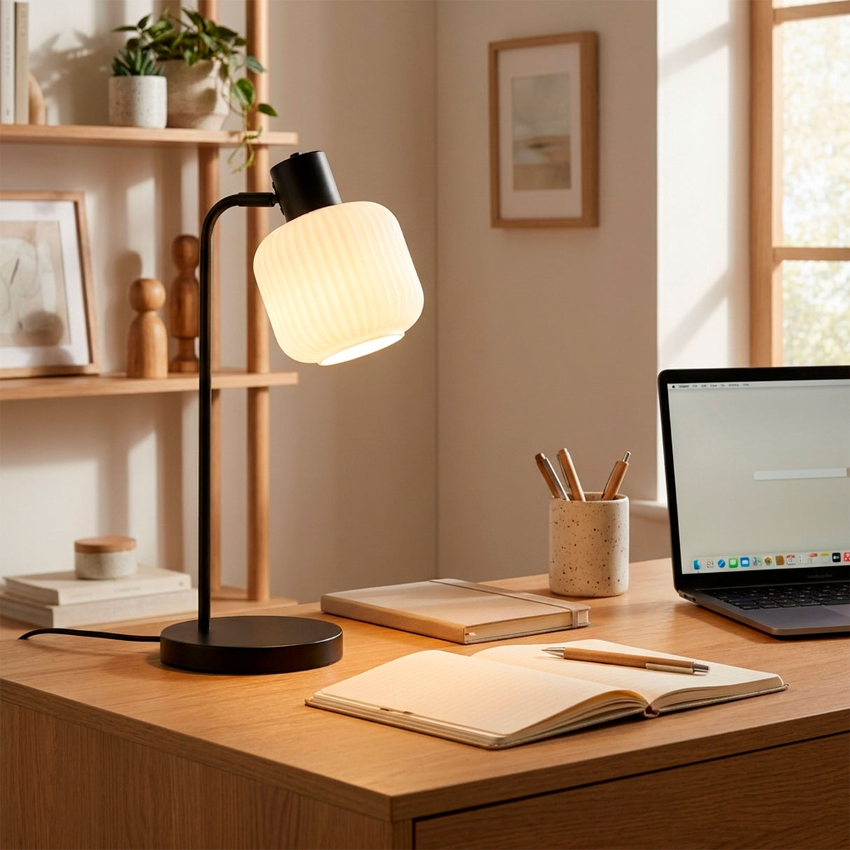 Lámpara de escritorio negra iluminando mesa de trabajo con decoración cálida