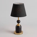 Lámpara de mesa ALBA BLACK AND GOLD negra y dorada sobre fondo gris neutro