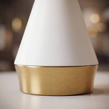 Primer plano de la base dorada cepillada y cono blanco mate de la lámpara AMIRA