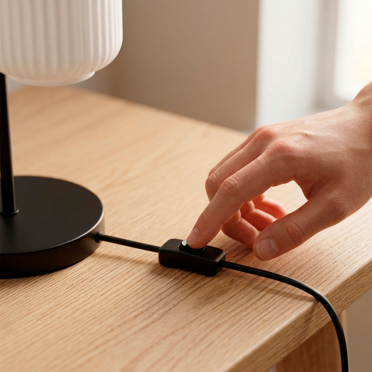 Mano conectando el cable de la lámpara de mesa negra en el escritorio