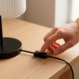 Mano conectando el cable de la lámpara de mesa negra en el escritorio