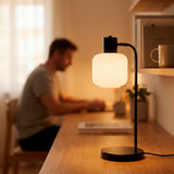 Hombre estudiando junto a la lámpara de mesa negra en su habitación