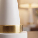 Primer plano del cono blanco mate y base dorada cepillada de la lámpara AURELIA