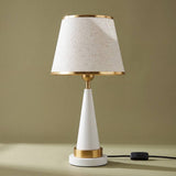 Lámpara de mesa AURELIA WHITE AND GOLD sobre fondo verde oliva elegante