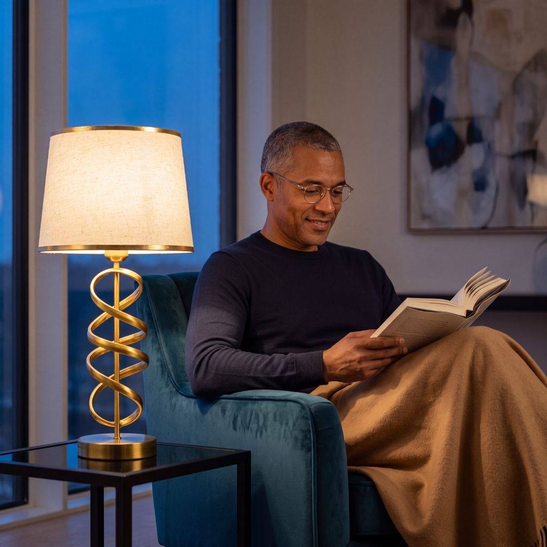 Hombre leyendo en el sillón junto a la luz cálida de la lámpara