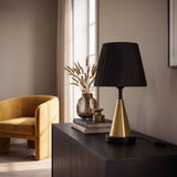 Lámpara decorativa negra y dorada junto a sillón en ambiente luminoso