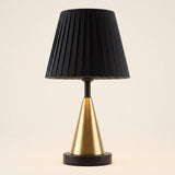 Lámpara de mesa con cono dorado y pantalla negra en ambiente claro