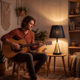 Persona tocando guitarra junto a la luz cálida de la lámpara de mesa