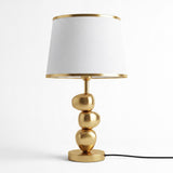 Lámpara de mesa dorada PIETRA GOLD con pantalla blanca sobre fondo neutro