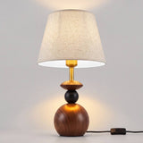 Lámpara de mesa FREYA WALNUT AND BLACK encendida en ambiente cálido de madera