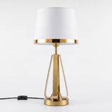 Lámpara de mesa Iris Gold con pantalla blanca sobre fondo blanco