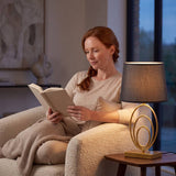 Mujer leyendo en el sillón junto a la luz cálida de la lámpara de mesa
