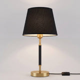 Lámpara de mesa negra con dorado en mesa auxiliar de sala luminosa