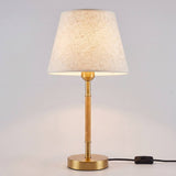 Lámpara de mesa MARGOT WOOD AND GOLD encendida con luz cálida y pantalla crema