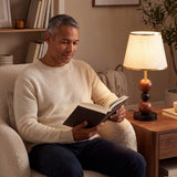 Hombre leyendo en el sillón junto a la luz cálida de la lámpara