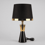 Lámpara de mesa negra con detalles dorados CLEO GOLD sobre fondo neutro