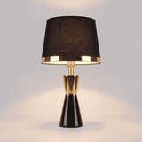 Lámpara de mesa negra con detalles dorados CLEO GOLD sobre fondo neutro