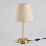 Lámpara de mesa NORA GOLD encendida con luz cálida y cable con interruptor visible