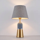 Lámpara de mesa OLIVIA GREY encendida con luz cálida en ambiente oscuro