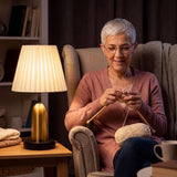 Mujer tejiendo en el sillón junto a la luz cálida de la lámpara