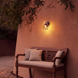 Lámpara de pared jaula iluminando terraza con sofá durante la noche