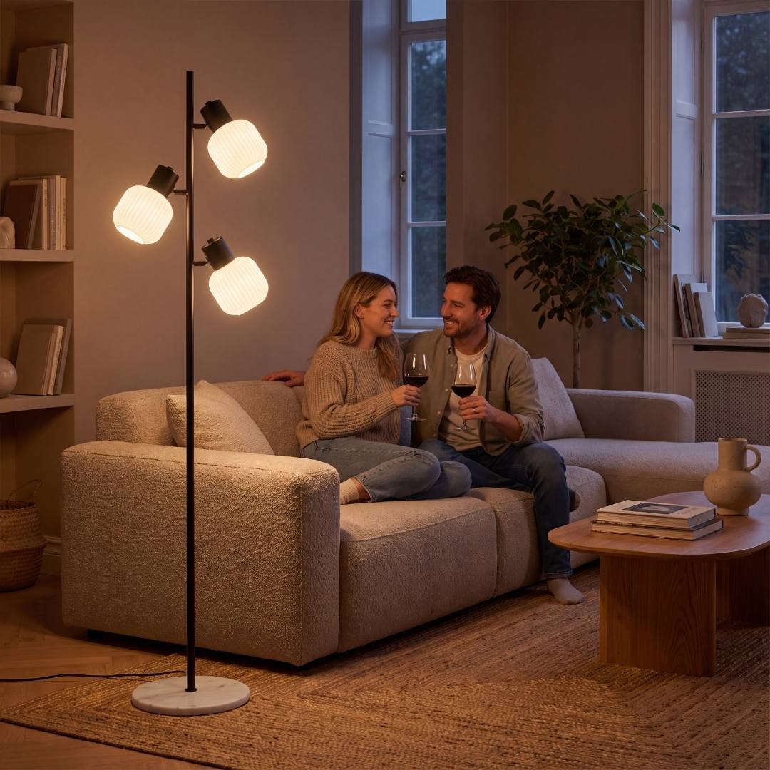 Pareja conversando en el sofá bajo la luz cálida de la lámpara de pie