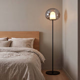 Lámpara de pie LED en dormitorio moderno junto a la cama con luz cálida