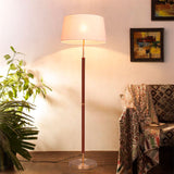 Lámpara de diseño clásico-moderno encendida junto a sillón de salón con manta tejida.