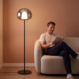 Hombre leyendo en butaca junto a la lámpara de pie LED ONIRA de luz cálida
