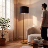 Hombre admirando la lámpara de pie negra encendida en sala con plantas