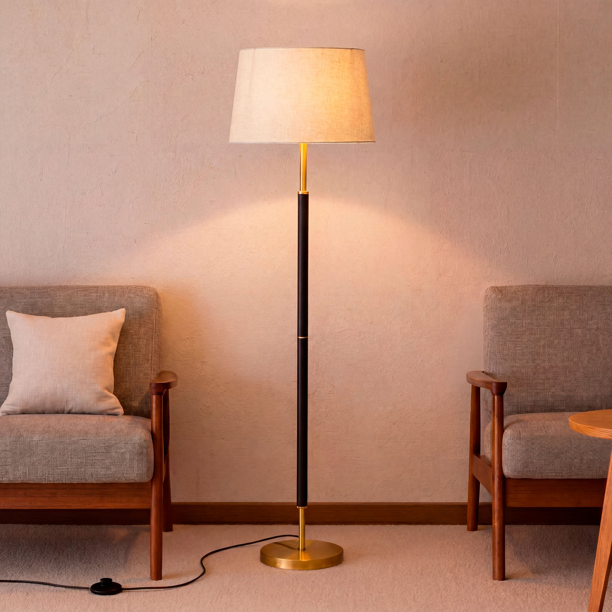 Lámpara de apoyo colocada entre dos sillones grises aportando una atmósfera relajante.