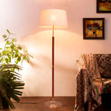 Lámpara de pie Jessica Gold Cedro con pantalla de lino junto a sillón con manta étnica.