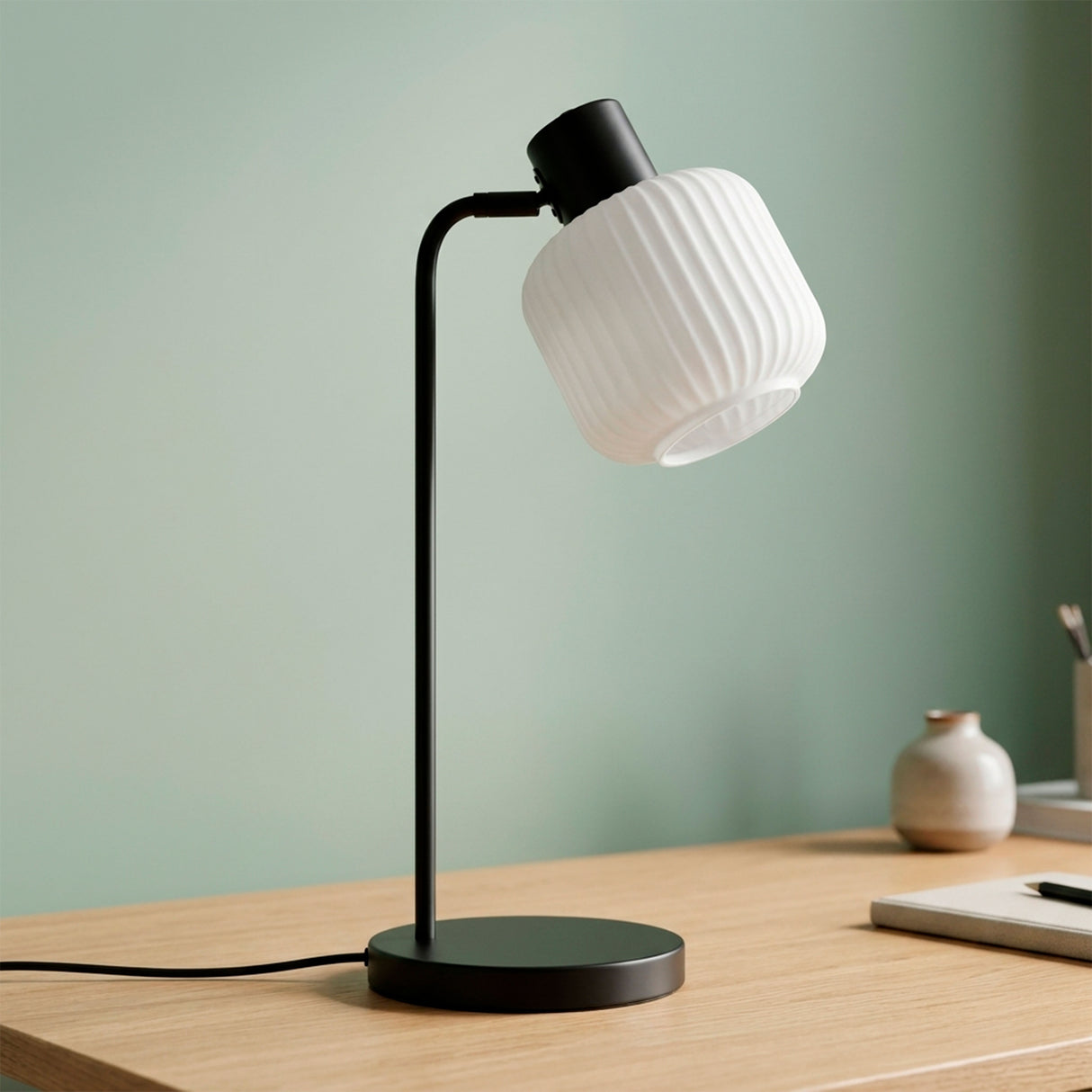 Lámpara decorativa ASTRID con luz cálida junto a planta y pared verde